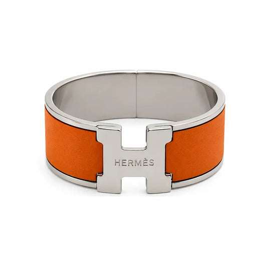 Hermes bracelet with orange band and silver clasp on a white background