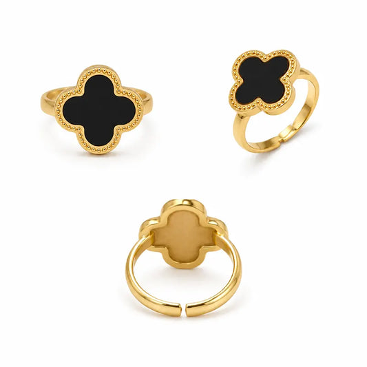 Three gold rings with black clover-shaped stones on a white background